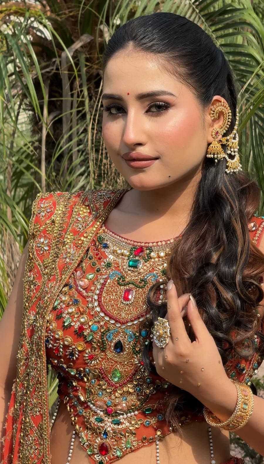 Bride outdoors with long styled hair and an embroidered green and gold outfit