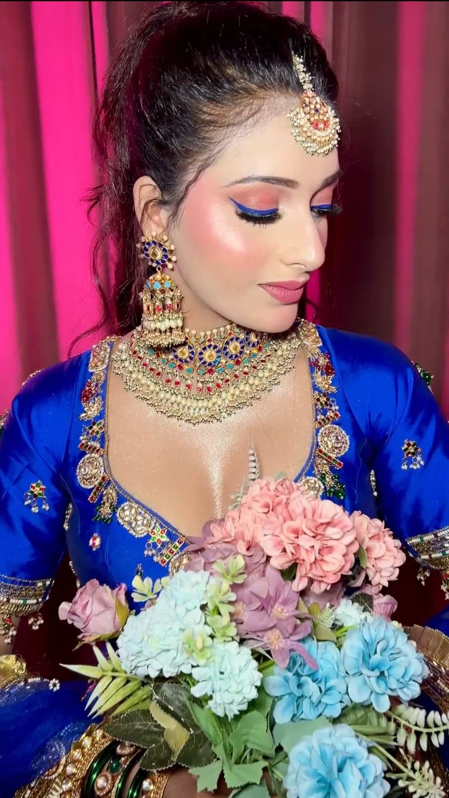 Bride in a blue outfit with colorful eye makeup and traditional jewellery